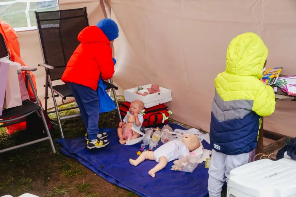 Dzieci w namiocie edukacyjnym oglądają lalki do nauki opieki nad noworodkiem